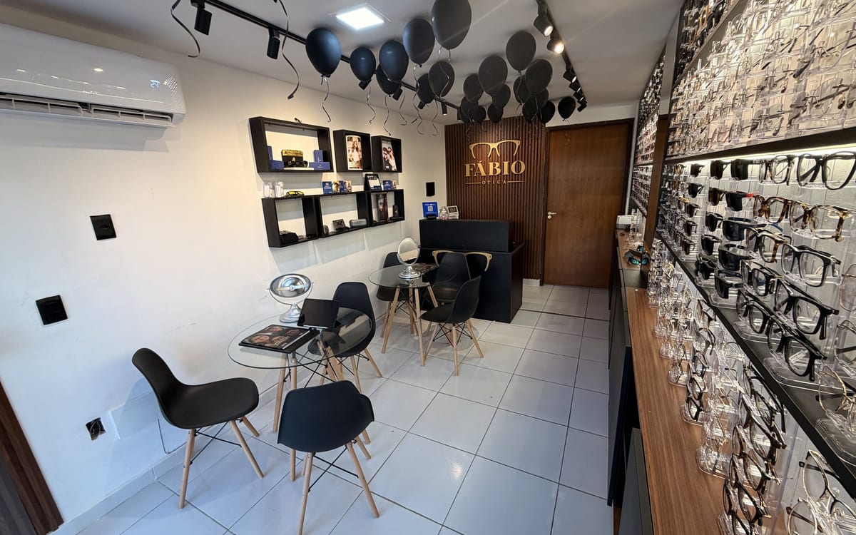 Visão geral do interior da Fábio Ótica, com recepção, mesas de atendimento e expositores